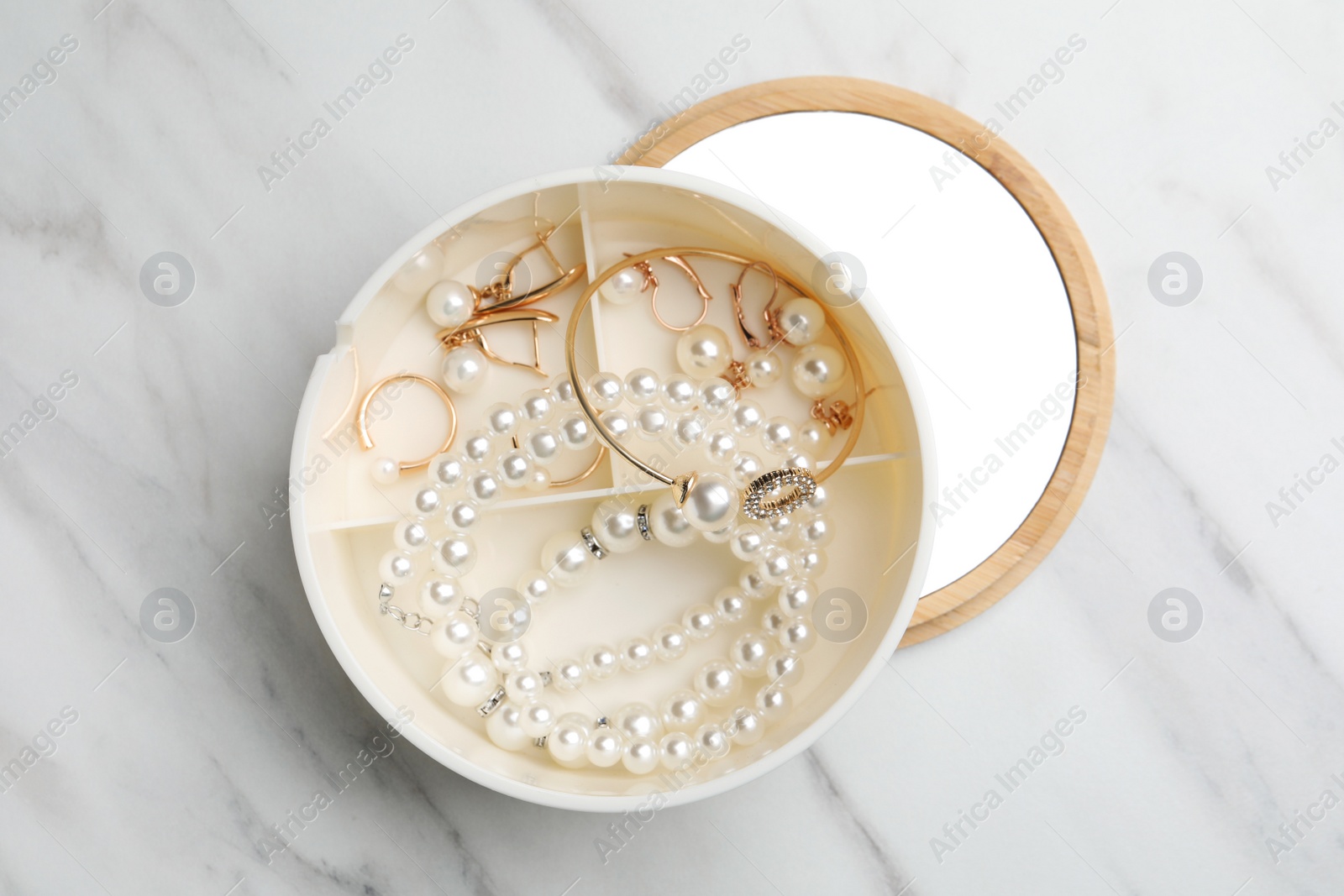 Photo of Stylish jewelry with pearls in box on white marble table, top view