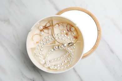 Stylish jewelry with pearls in box on white marble table, top view