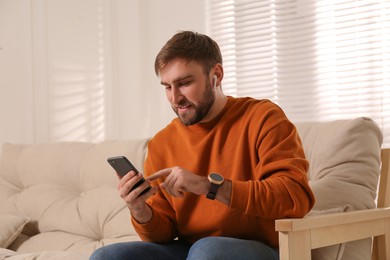 Young man with smart watch, phone and earphones at home