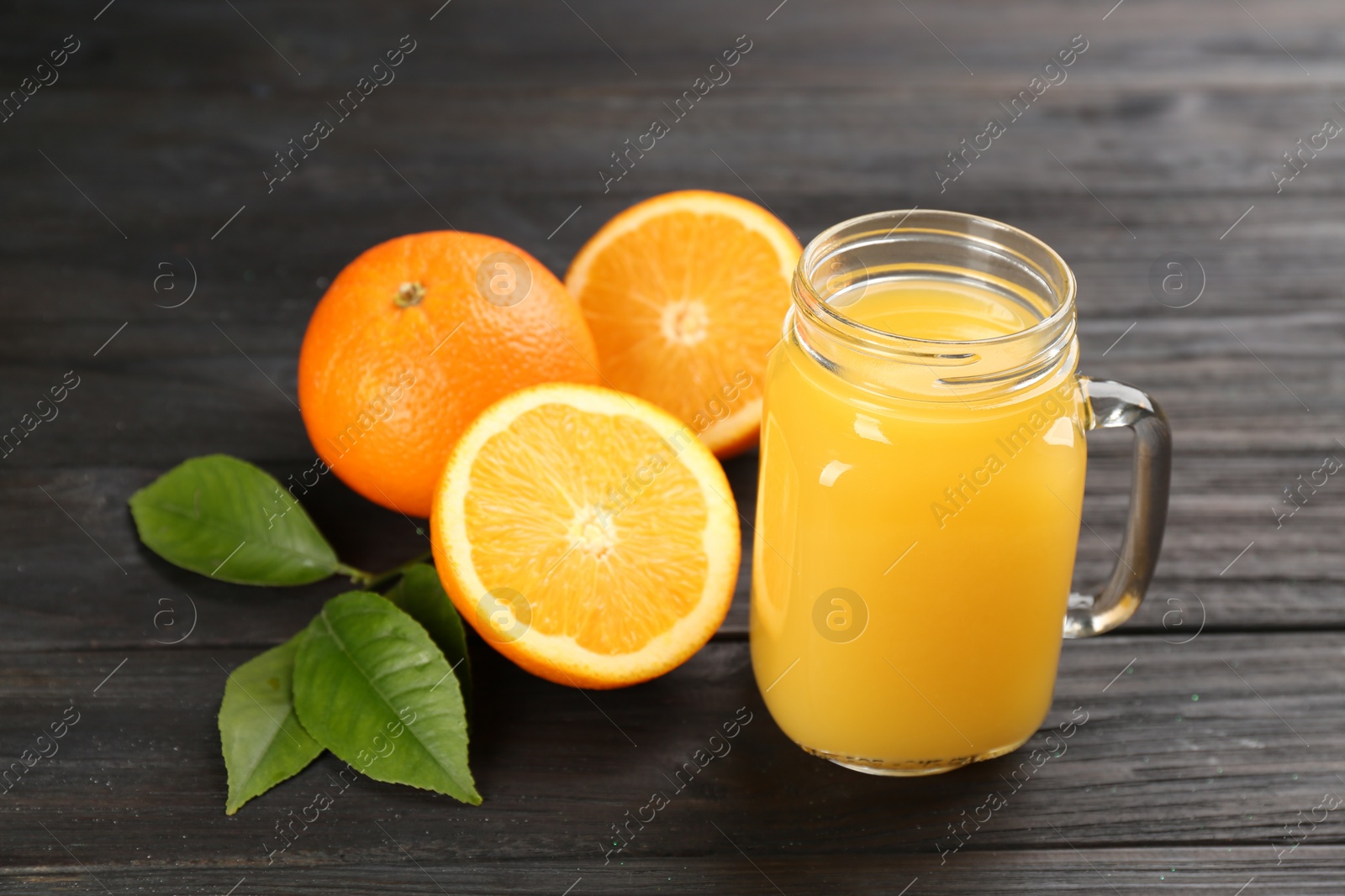 Photo of Delicious orange juice and fresh fruits on black wooden table