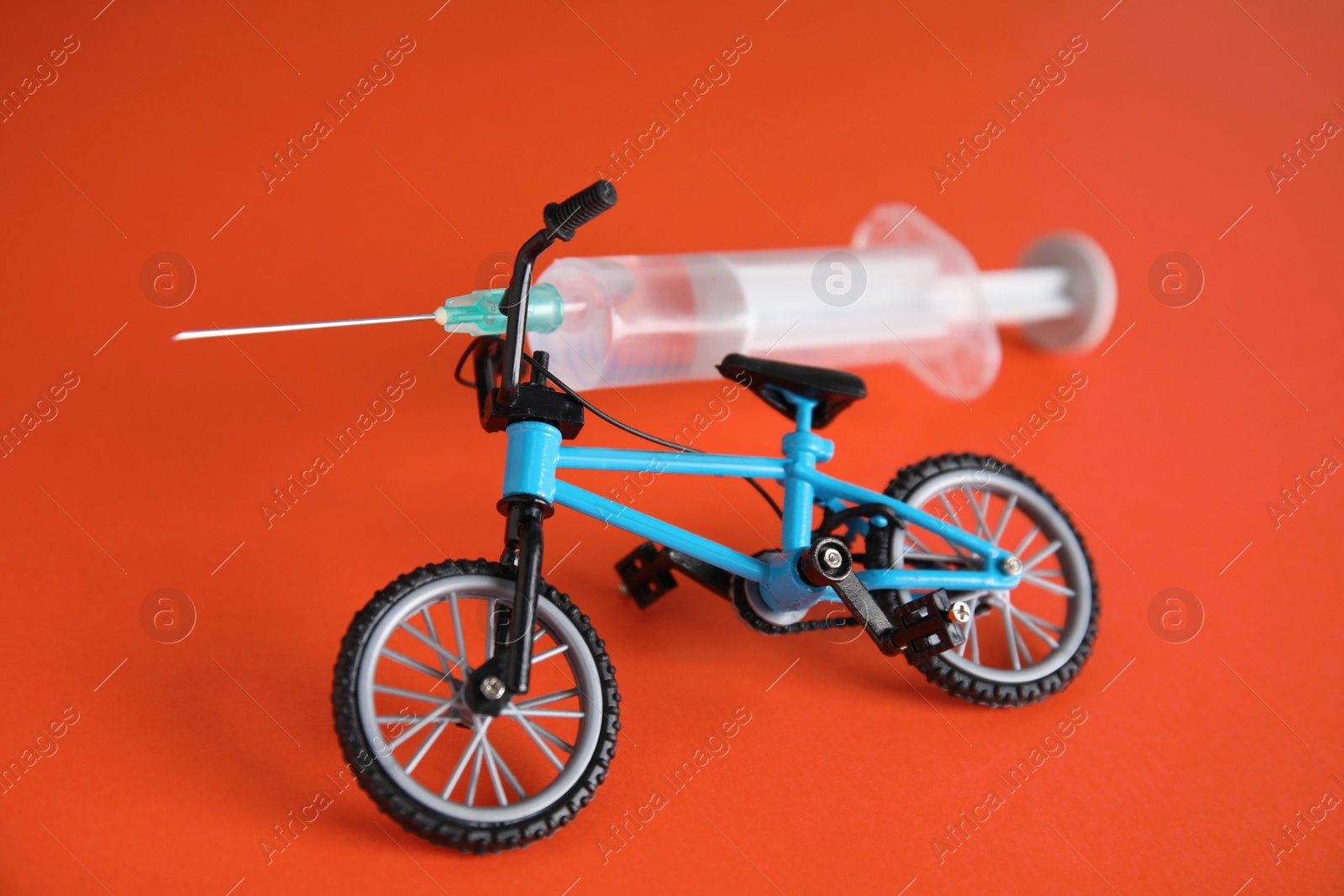 Photo of Bike model and syringe on red background. Using doping in cycling sport concept