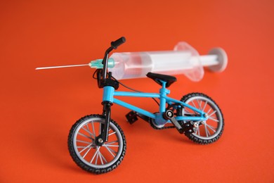 Photo of Bike model and syringe on red background. Using doping in cycling sport concept