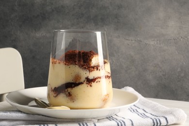 Delicious tiramisu in glass on table, closeup. Space for text