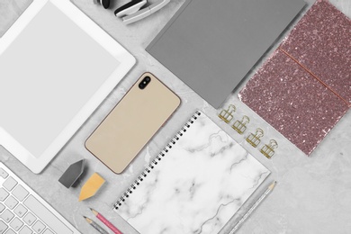 Flat lay composition with tablet, phone and notebook on grey marble table. Designer's workplace