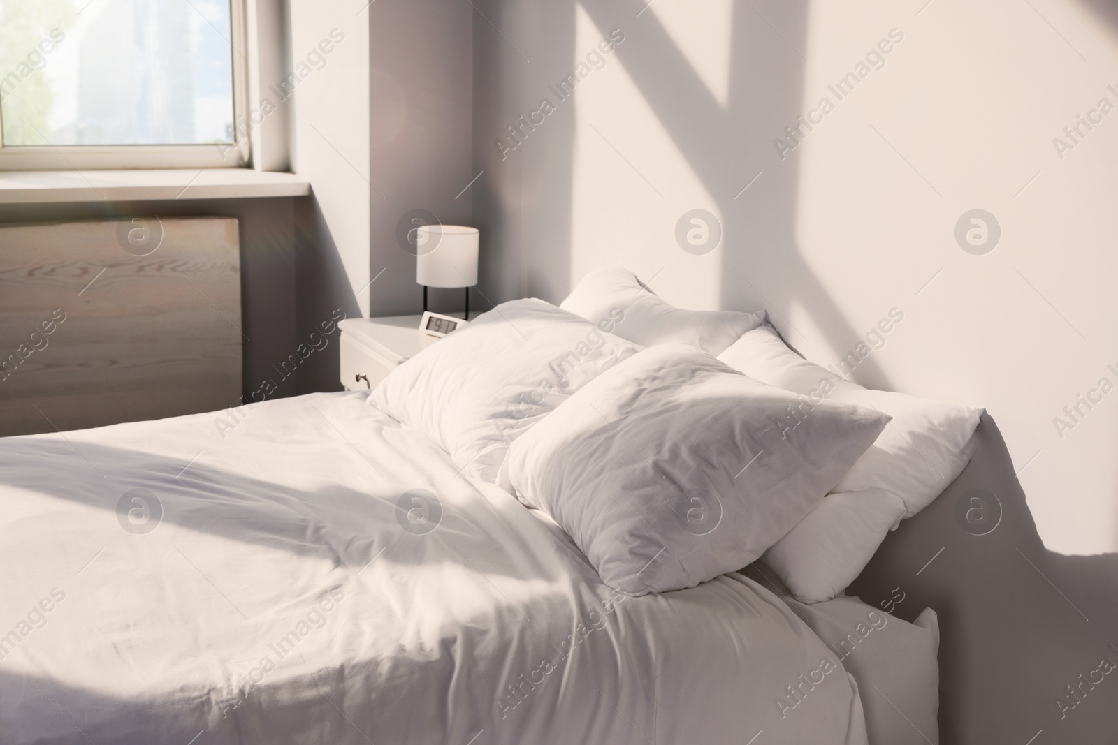 Photo of White soft pillows on bed in room