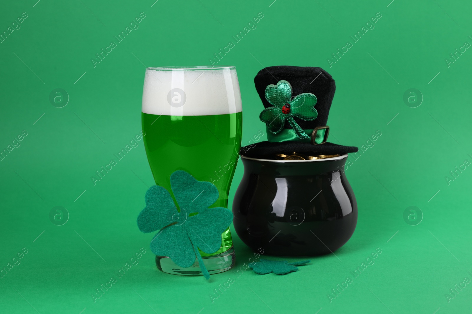 Photo of St. Patrick's day party. Green beer, leprechaun hat, pot of gold and decorative clover leaves on green background