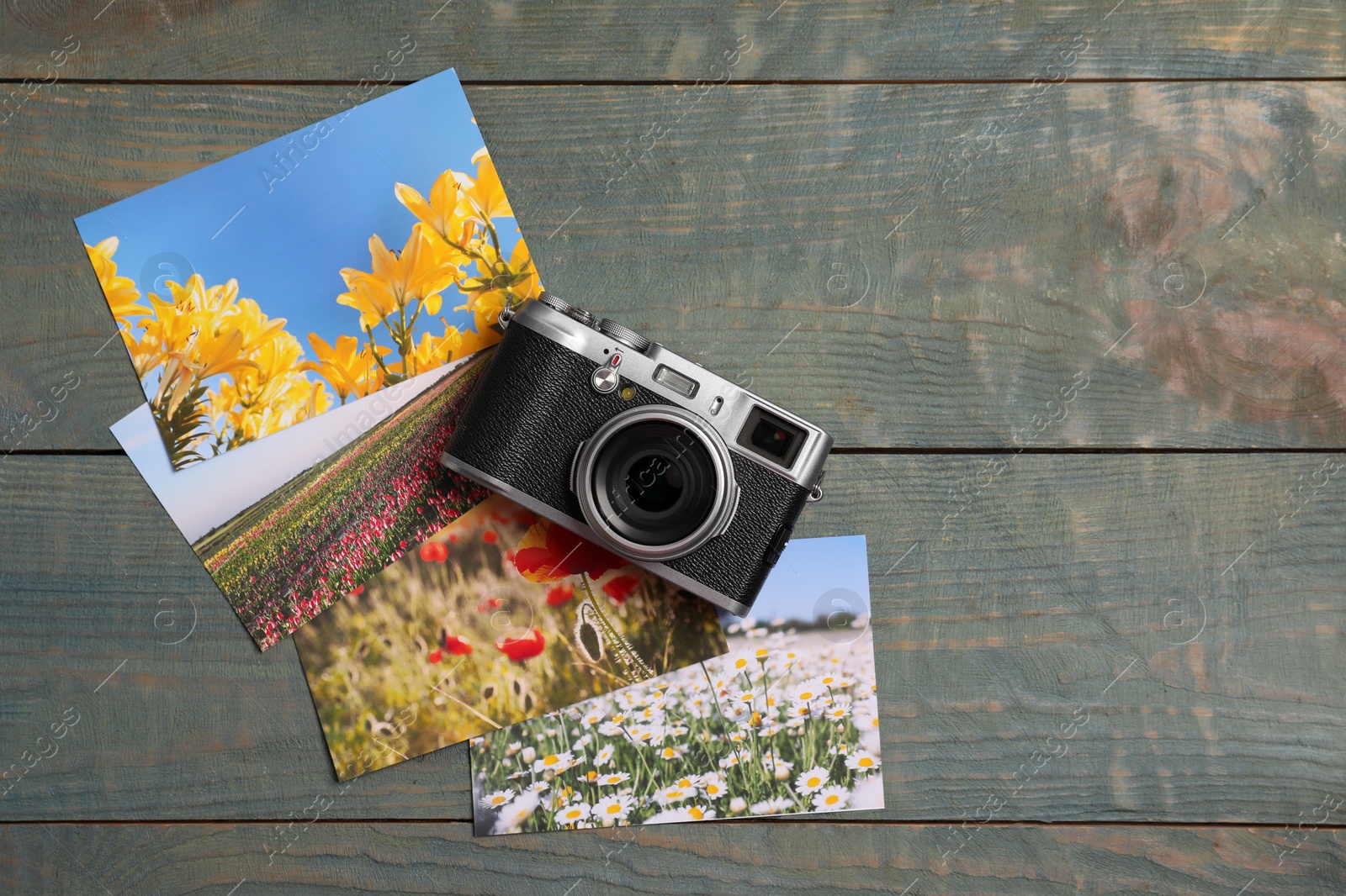 Photo of Vintage photo camera and beautiful printed pictures on wooden table, flat lay with space for text. Creative hobby