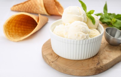 Photo of Bowl of ice cream and mint leaves on white table