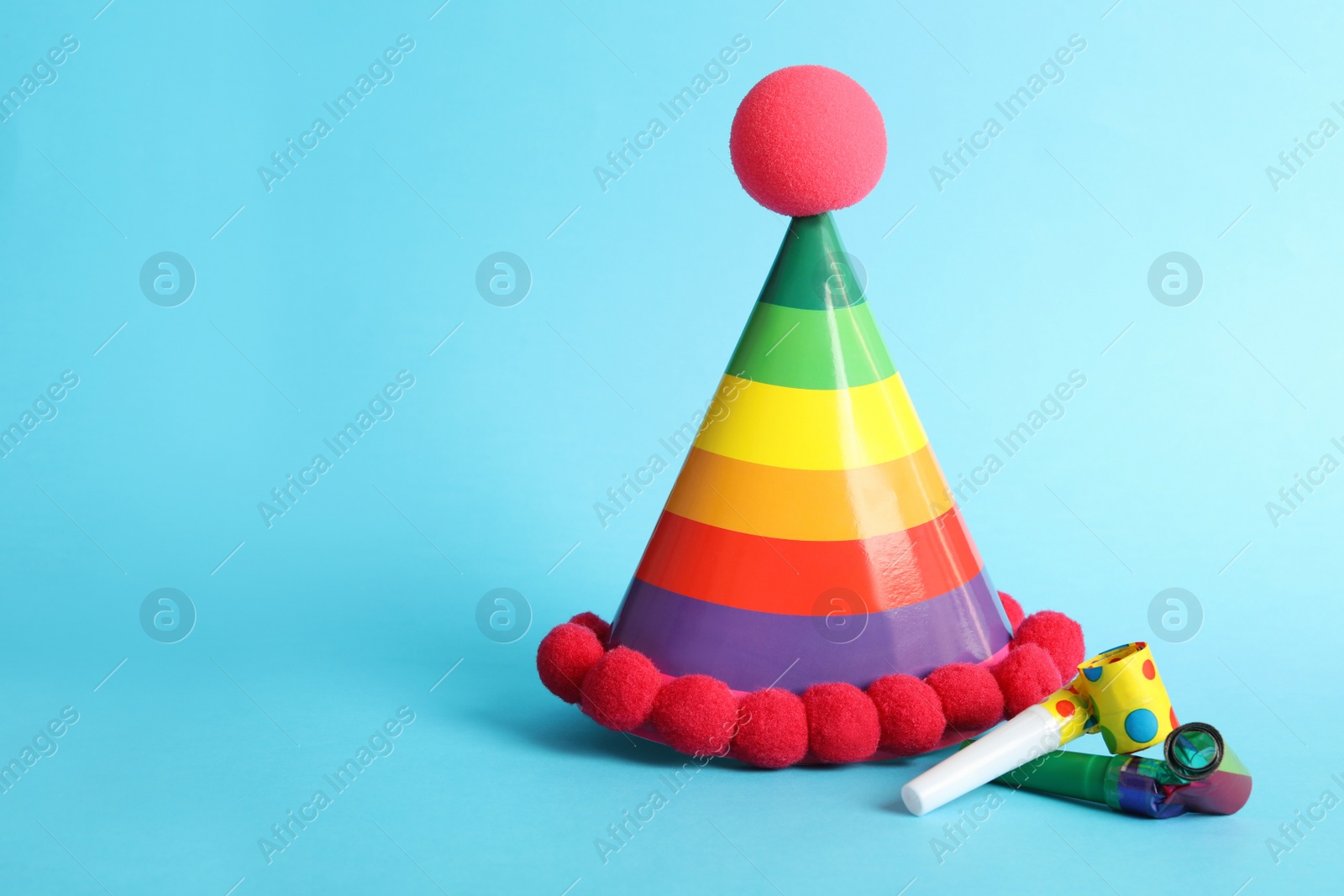 Photo of Party cap and blowers on light blue background, space for text