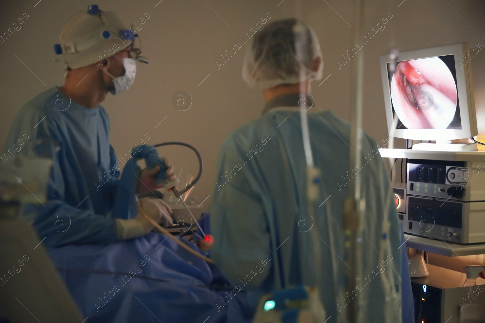 Photo of Professional doctors performing 
frontal sinus trephination with modern equipment in surgery room