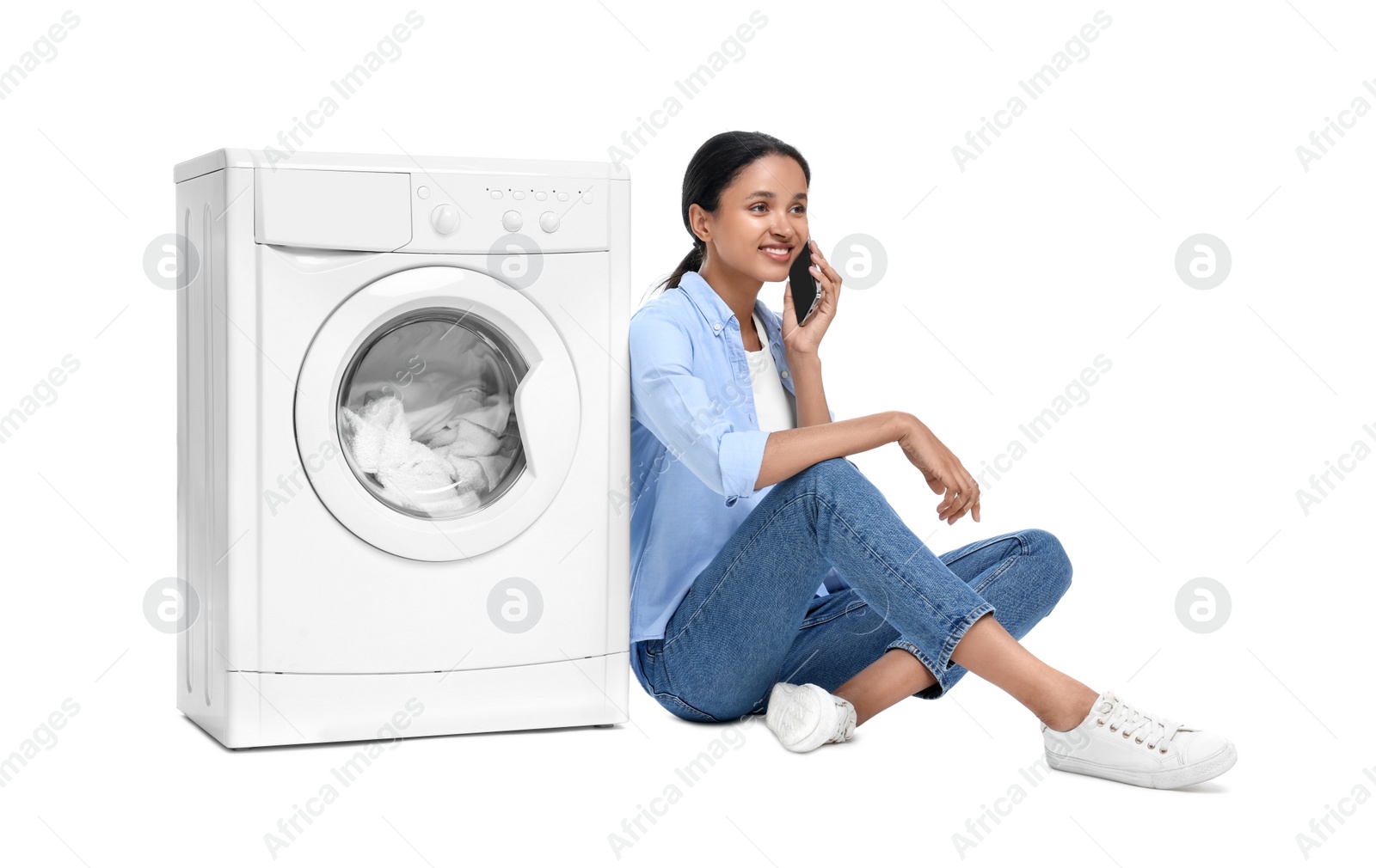 Photo of Beautiful woman talking on phone near washing machine against white background