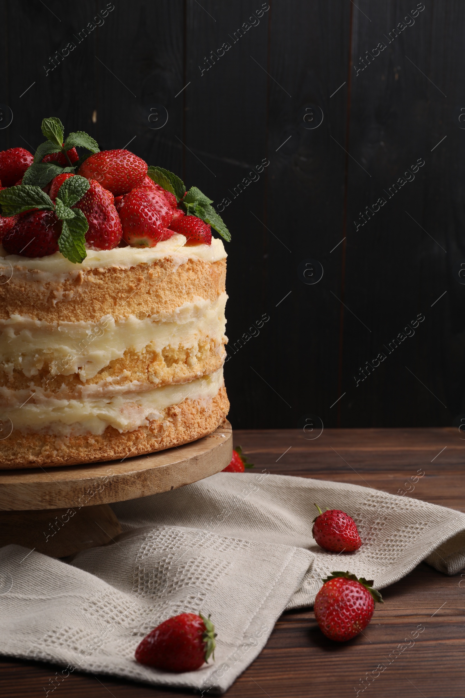 Photo of Tasty cake with fresh strawberries and mint on wooden table, closeup. Space for text