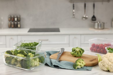 Containers with different fresh products on white marble table, space for text. Food storage