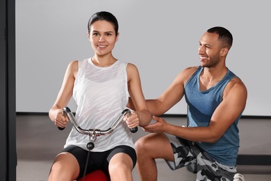 Happy trainer explaining woman how to do exercise properly in modern gym