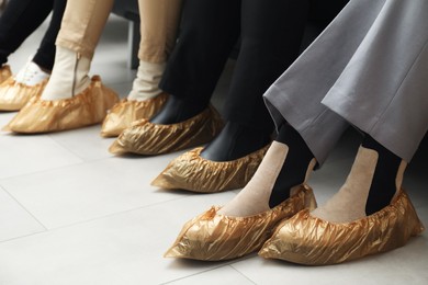 Photo of Women wearing shoe covers onto different footwear indoors, closeup