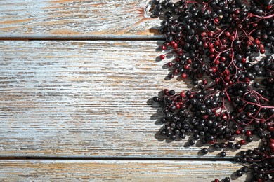 Photo of Black elderberries (Sambucus) on old wooden table, flat lay. Space for text