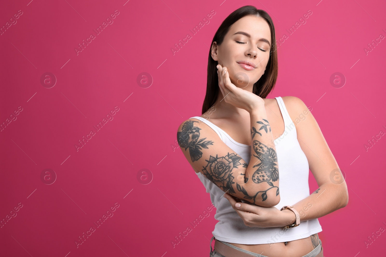 Photo of Beautiful woman with tattoos on arm against pink background. Space for text