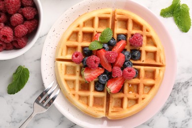 Photo of Tasty Belgian waffle with fresh berries served on white marble table, flat lay