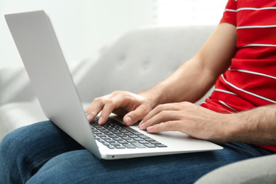 Photo of Man working on modern laptop at home, closeup