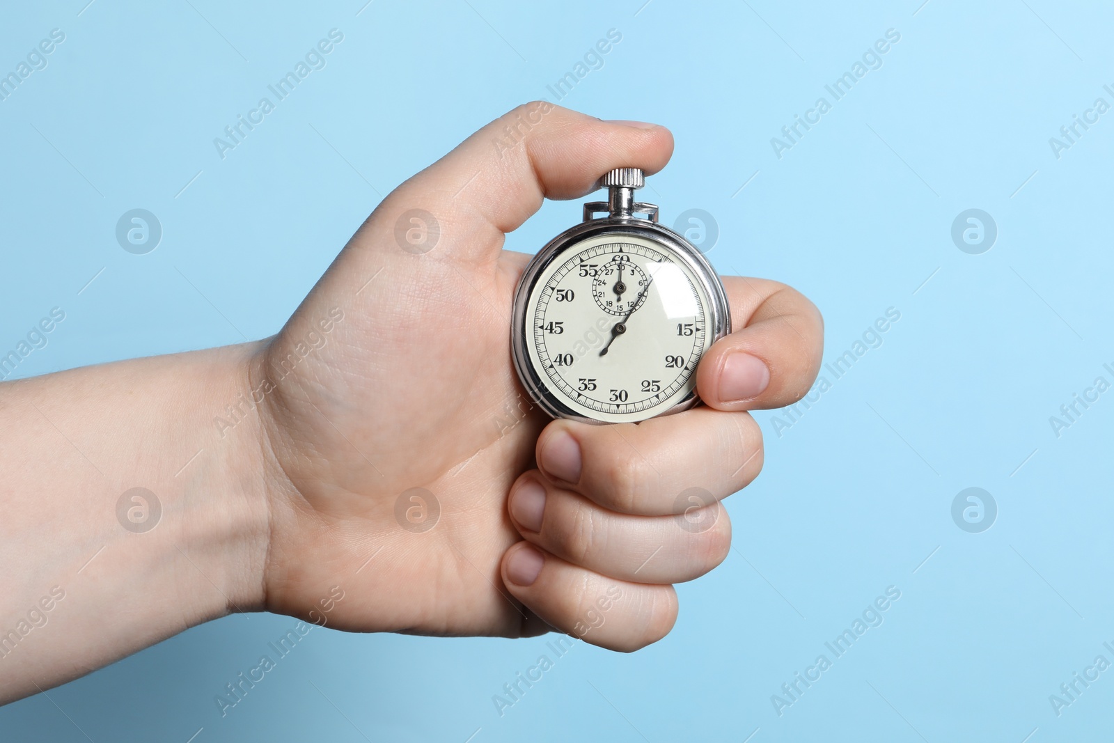 Photo of Man holding vintage timer on light blue background, closeup