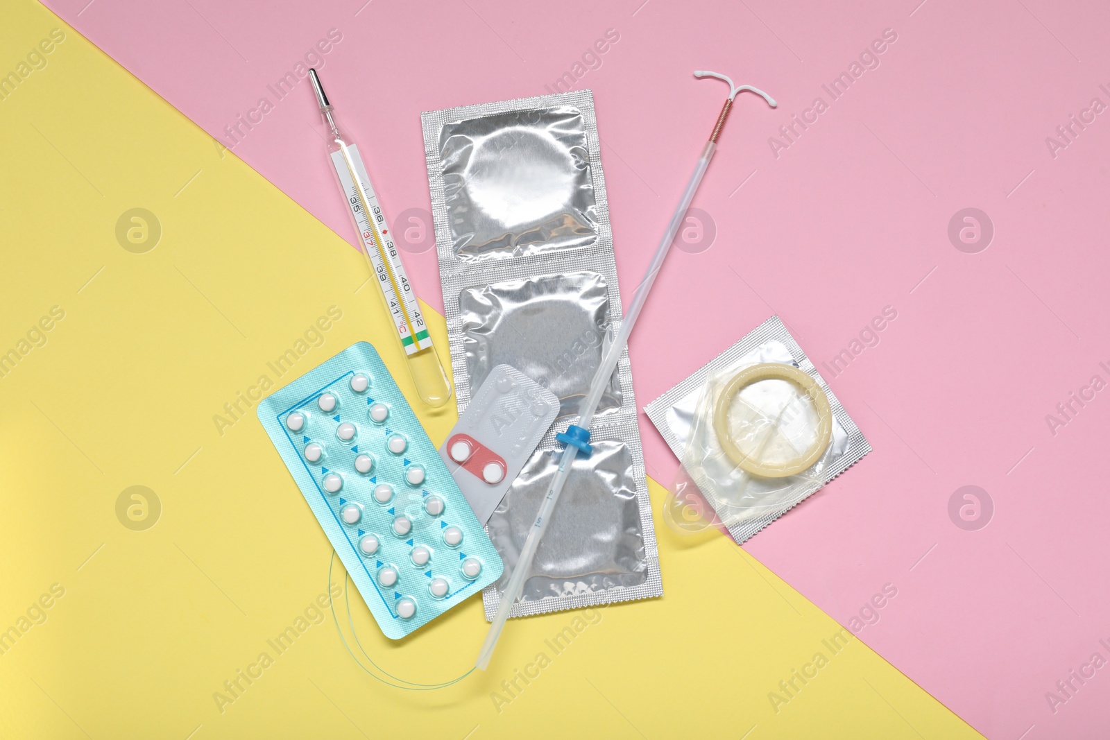 Photo of Contraceptive pills, condoms, intrauterine device and thermometer on color background, flat lay. Choice of birth control method