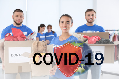 Image of Volunteers uniting to help during COVID-19 outbreak. Group of people with donations indoors, shield and world globe illustrations