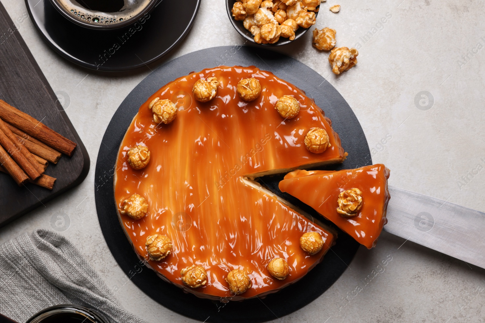 Photo of Sliced delicious caramel cheesecake with popcorn served on light grey table, flat lay