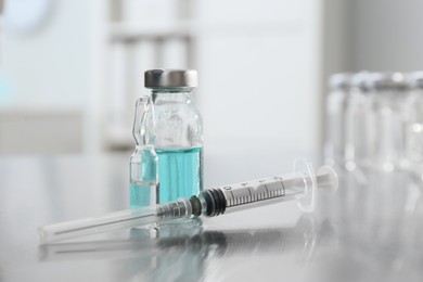 Photo of Syringe with vial and ampule of medicines on table, closeup
