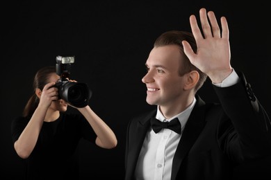 Professional photographer taking picture of man on black background