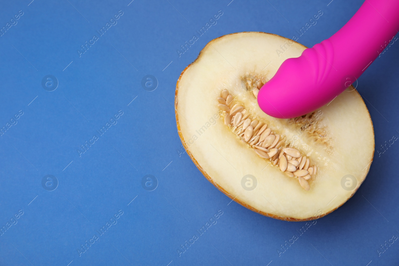 Photo of Half of melon and purple vibrator on blue background, flat lay with space for text. Sex concept