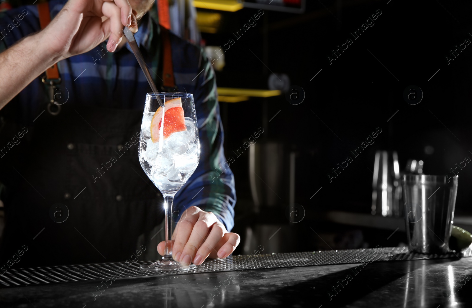 Photo of Barman making grapefruit gin tonic cocktail at counter in pub, closeup. Space for text