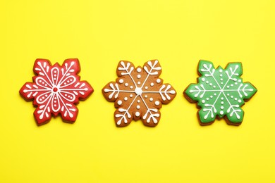 Photo of Tasty Christmas cookies in shape of snowflakes on yellow background, flat lay