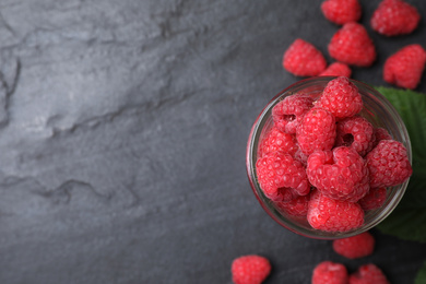 Photo of Delicious fresh ripe raspberries on black table, flat lay. Space for text