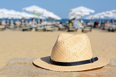 Photo of Stylish straw hat on stone surface near sea, space for text