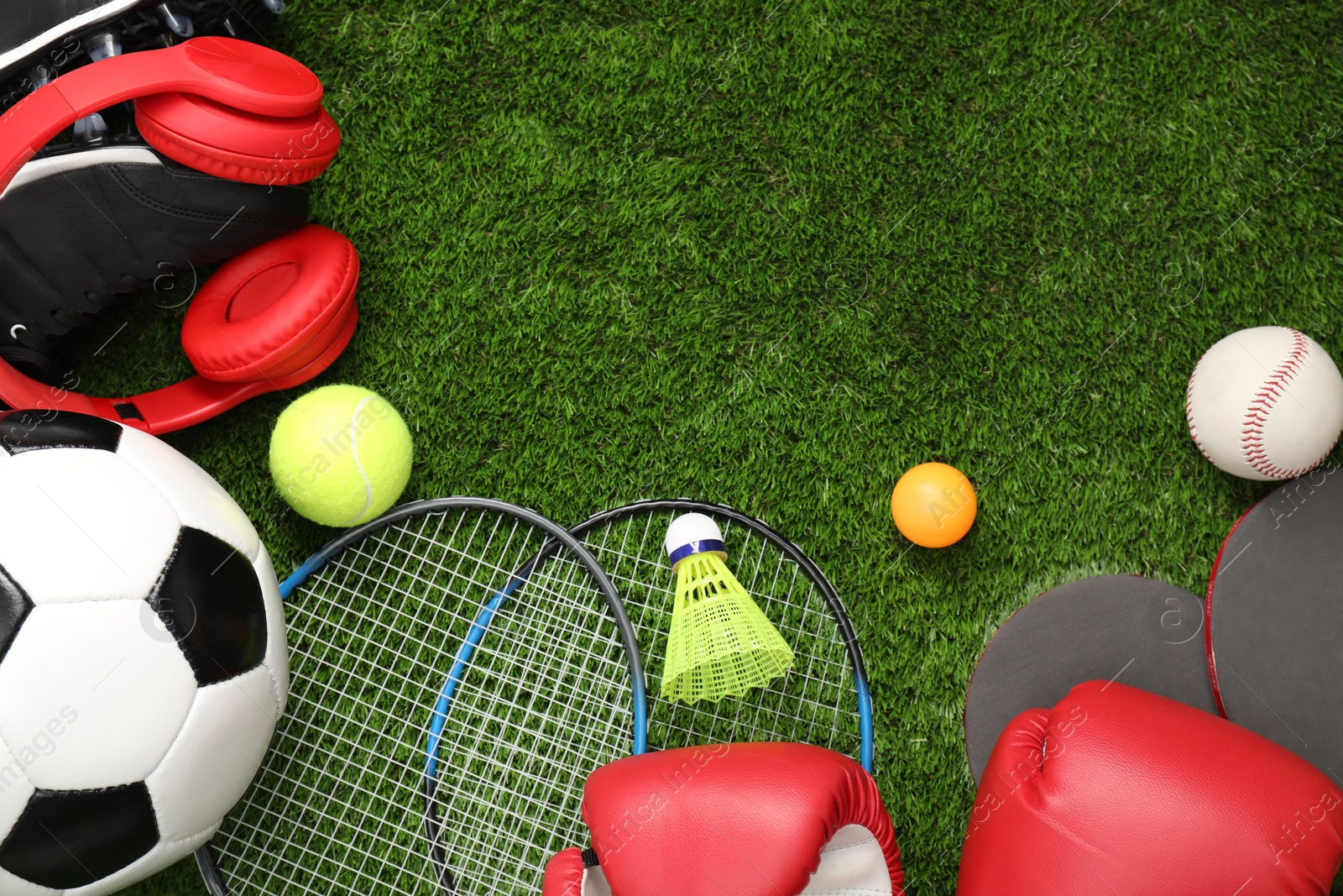 Photo of Different sports equipment on green grass, flat lay. Space for text