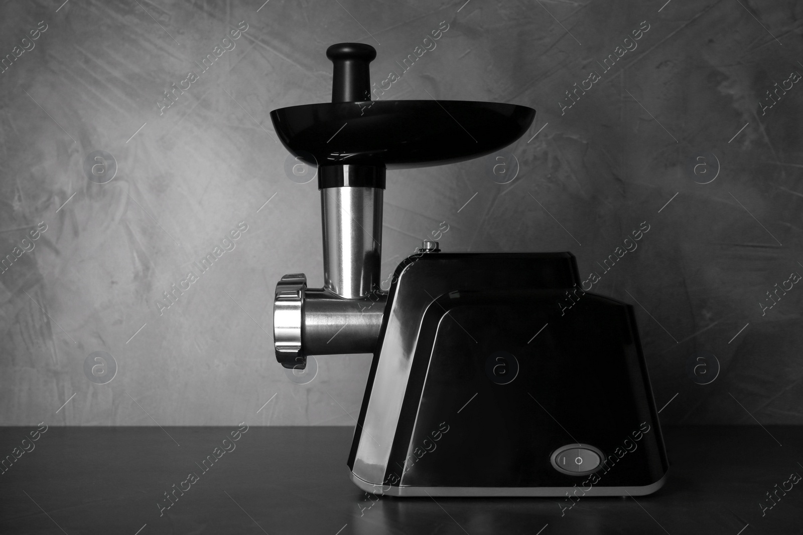 Photo of Modern electric meat grinder on black table. Space for text