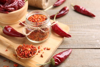 Photo of Chili pepper flakes and pods on wooden table, space for text