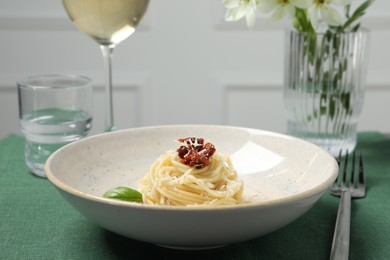 Photo of Tasty spaghetti with sun-dried tomatoes and parmesan cheese served on table, closeup. Exquisite presentation of pasta dish