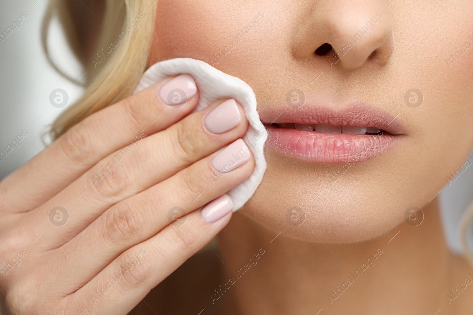 Photo of Woman removing makeup with cotton pad, closeup