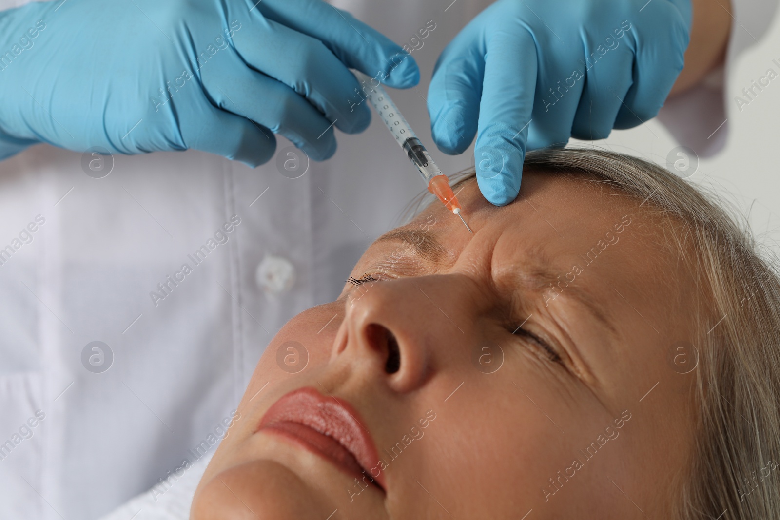 Photo of Doctor giving facial injection to senior woman in clinic, closeup. Cosmetic surgery