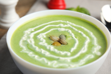 Photo of Bowl of delicious broccoli cream soup with pumpkin seeds, closeup