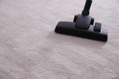 Photo of Modern vacuum cleaner on carpet indoors. Space for text