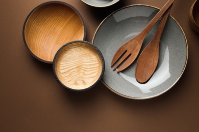 Photo of Stylish empty dishware and wooden cutlery on brown background, flat lay