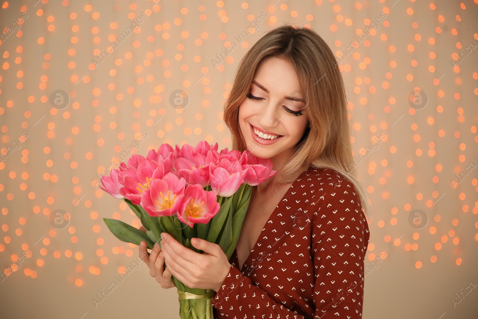 Photo of Portrait of smiling young girl with beautiful tulips on blurred background. International Women's Day