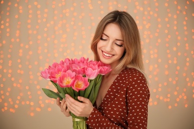 Portrait of smiling young girl with beautiful tulips on blurred background. International Women's Day