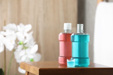 Photo of Bottles with mouthwash on wooden table in bathroom, space for text