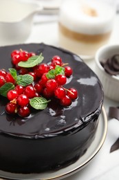 Photo of Tasty homemade chocolate cake with berries and mint on white table, closeup