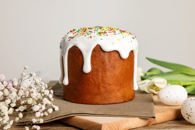 Tasty Easter cake, decorated eggs and flowers on wooden table