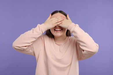 Photo of Woman covering eyes and laughing on violet background