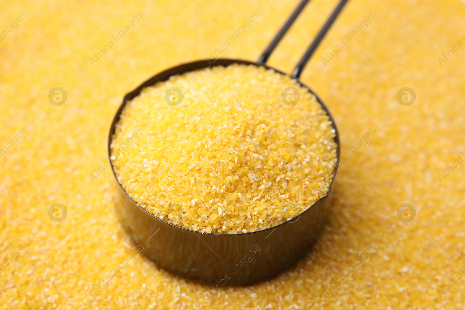 Photo of Metal scoop on raw corn grits, closeup